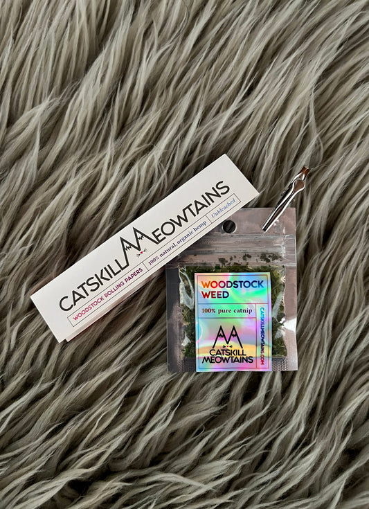 Catskill Meowtains book of 100% natural, organic hemp rolling papers and a nickle bag size package of Woodstock Weed organic catnip with a roach clip